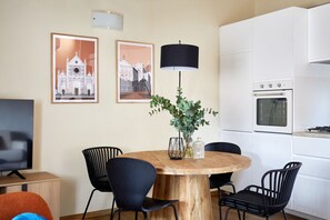 A modern kitchen with white cabinets, a round wooden table, black chairs, and a black lamp. - Casa Negroni, ancient house in front of medieval walls (Firenze)