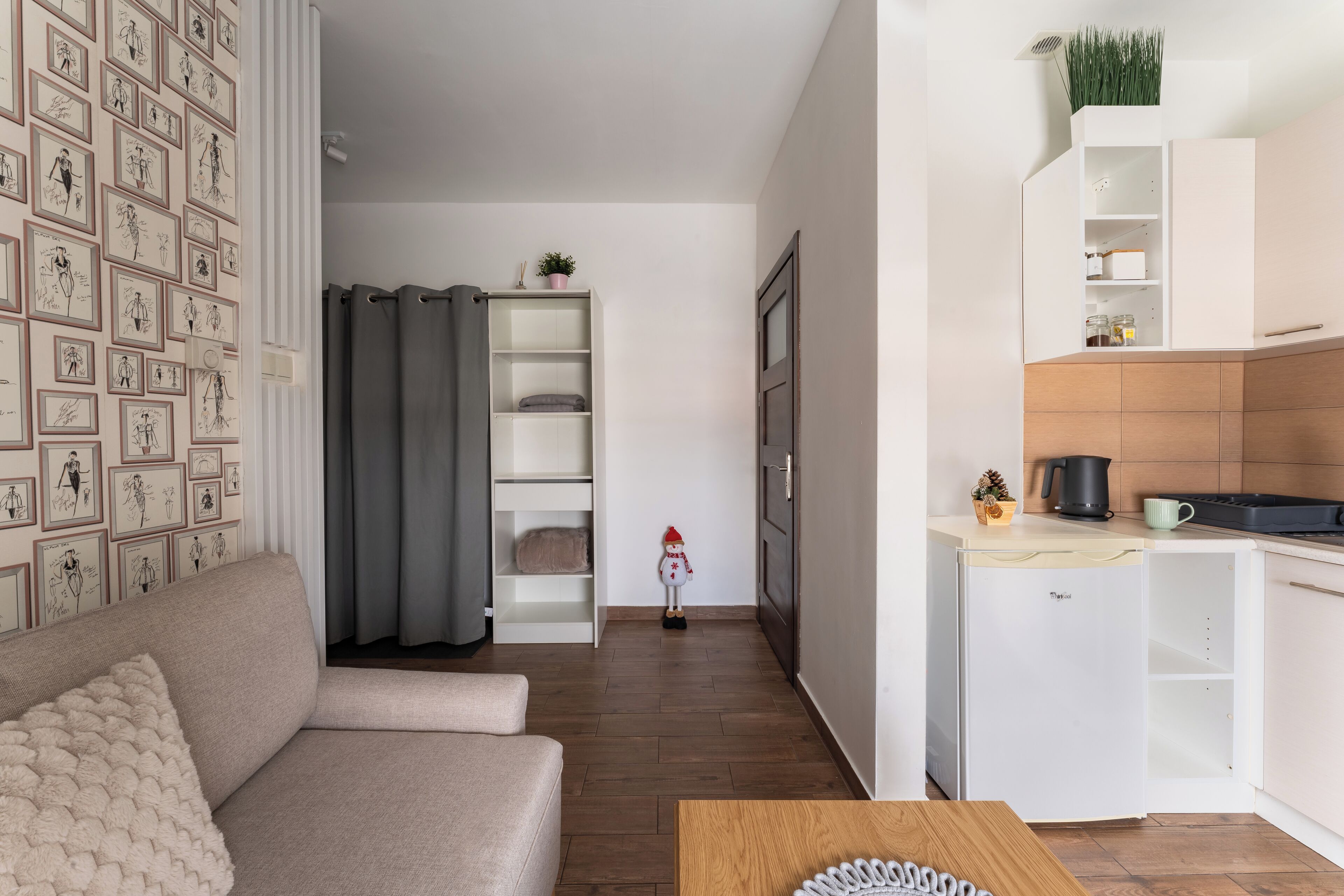 A modern living room with a sofa, a coffee table, and a kitchen area with a refrigerator and cabinets.
