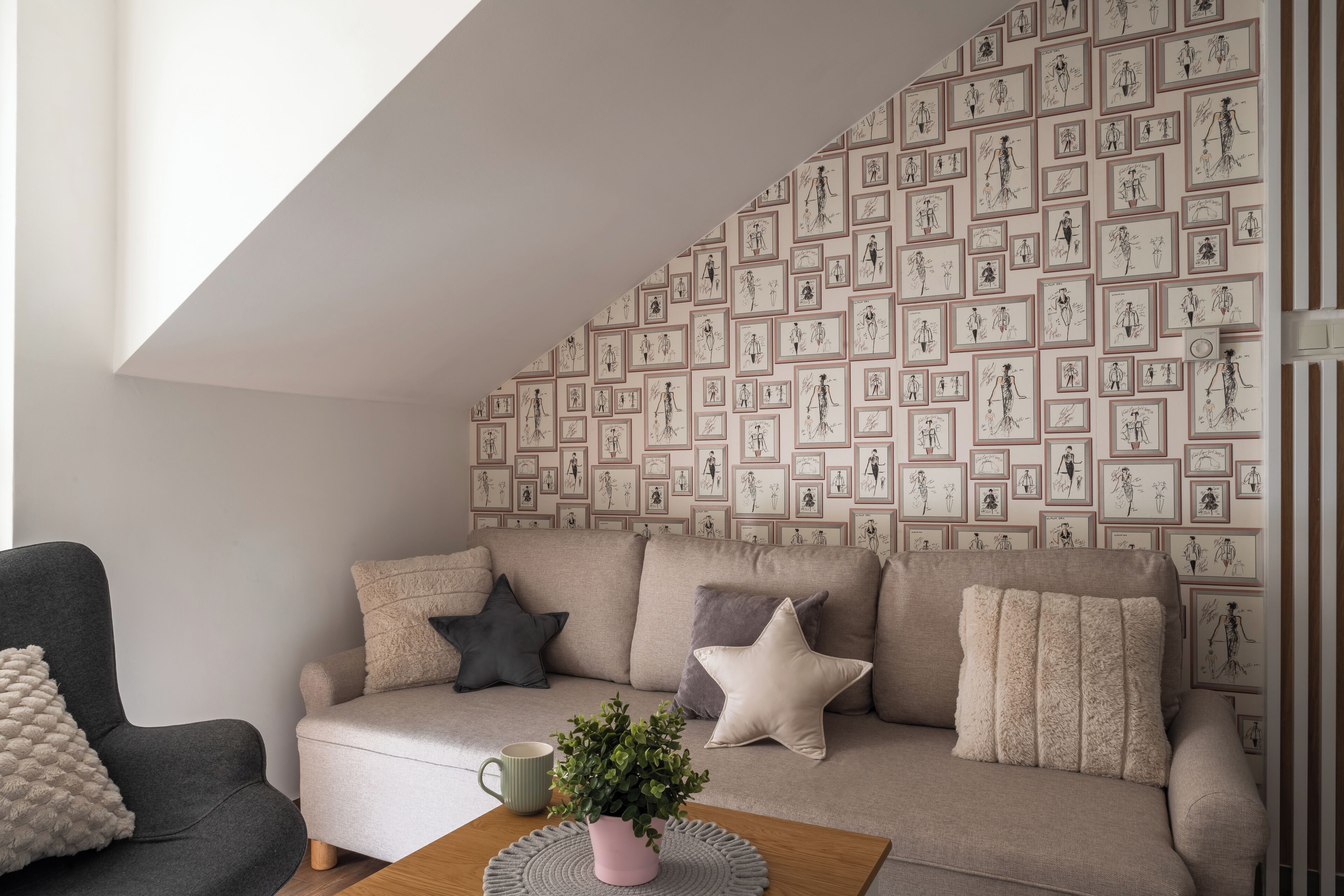 A modern living room with a sofa, a coffee table, and a wall decorated with framed sketches.