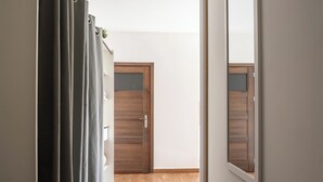 Ein Flur mit Holzboden, einer Tür mit Spiegel und einer Reihe Vorhänge.