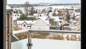 Blick aus einem Fenster auf ein Wohngebiet mit Häusern und einem fernen Gebirge.