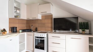 Eine moderne Küche mit weißen Schränken, einem eingebauten Backofen, einem großen Flachbildfernseher und Holzboden.