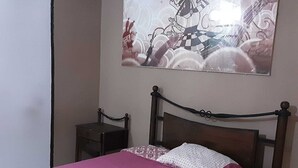 Ein Schlafzimmer mit einem Bett, einem Nachttisch und einem an der Wand hängenden Gemälde.
