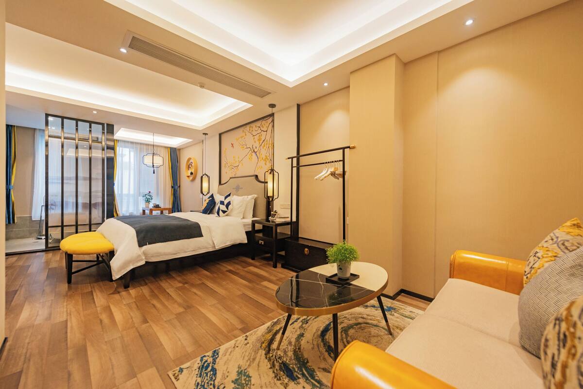 Una habitación de hotel moderna con una cama, un sofá, una mesa de centro y una pequeña mesa con una planta.