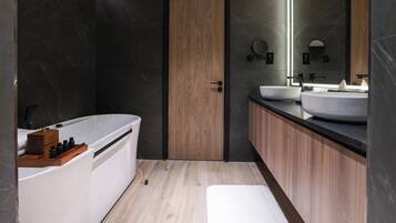 Un baño moderno con puerta de madera, bañera blanca y un espejo grande sobre un lavabo.