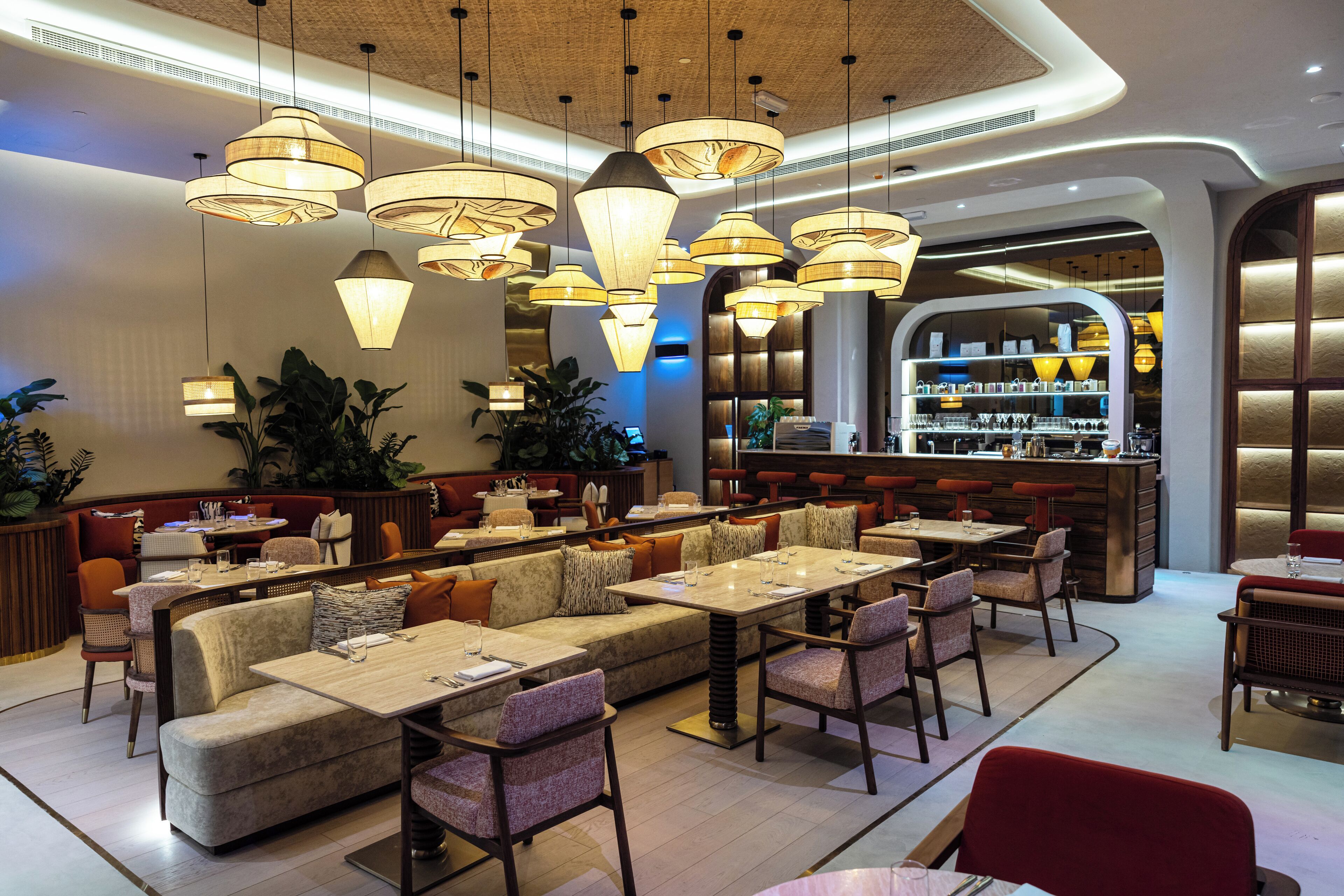 Um restaurante moderno com pé-direito alto, iluminação pendente e um espaço bar.