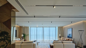 A modern living room with a large window, two sofas, a coffee table, and a floor lamp. - The OQ (Lusail)