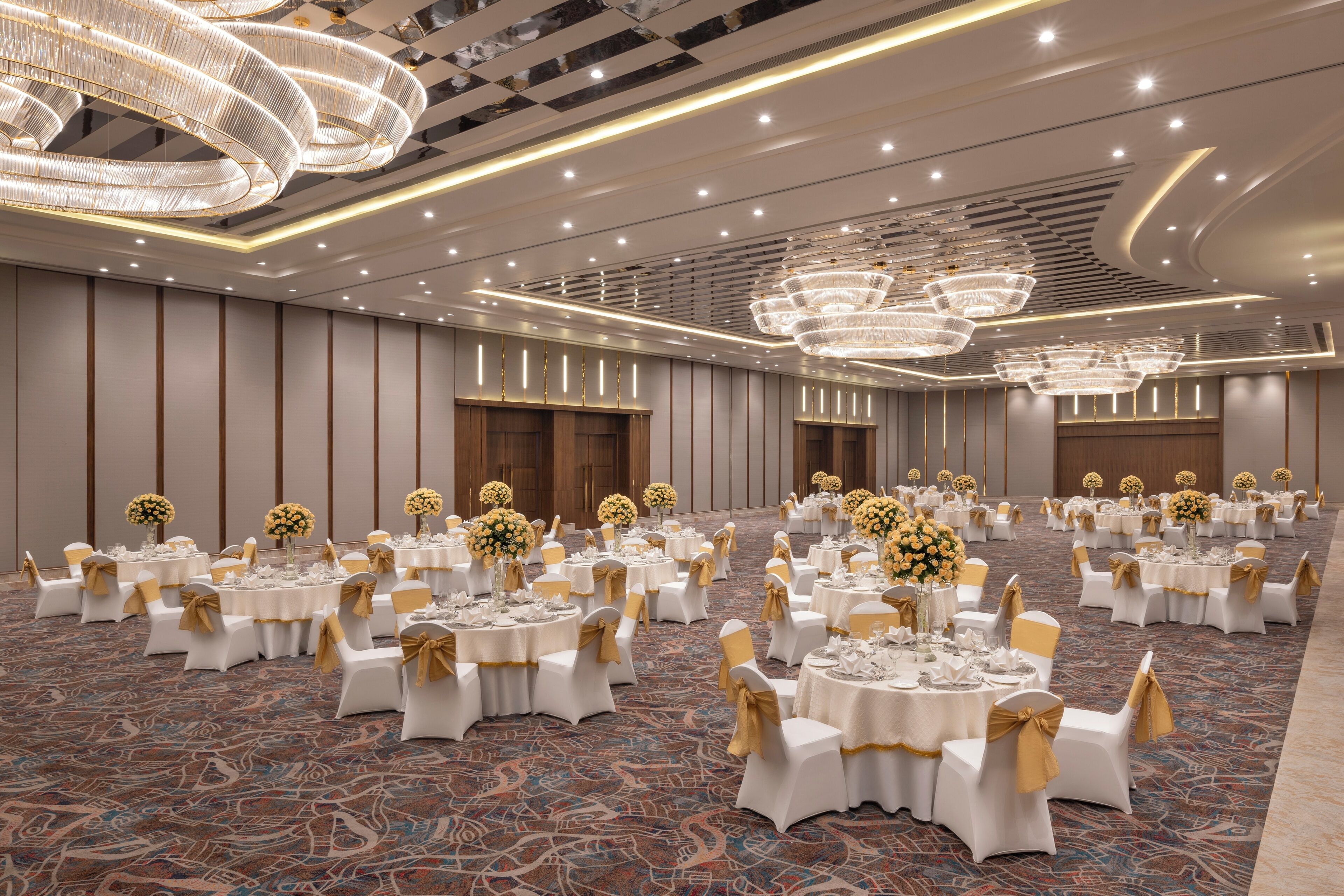 A banquet hall with round tables, white chairs, and gold sashes.