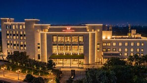 A modern hotel with a prominent entrance, multiple floors, and a well-lit facade. - Welcomhotel By ITC Hotels Delhi-Gurugram Highway (Gurugram)