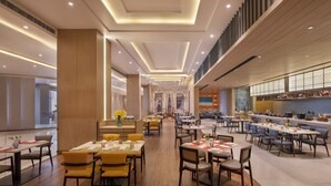 A spacious restaurant with multiple dining areas, wooden flooring, and modern lighting. - Welcomhotel By ITC Hotels Delhi-Gurugram Highway (Gurugram)