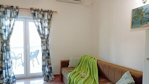 A living room with a sofa, a green blanket, and a painting on the wall.