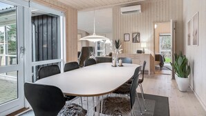 Un espace repas moderne avec une grande table, des chaises noires et un luminaire suspendu blanc.
