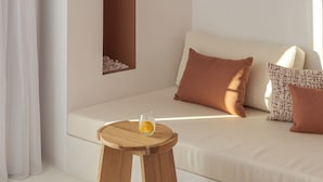 A modern living room with a sofa, a wooden stool, and a glass of orange juice. - Aegean Colors Paros (Paros)