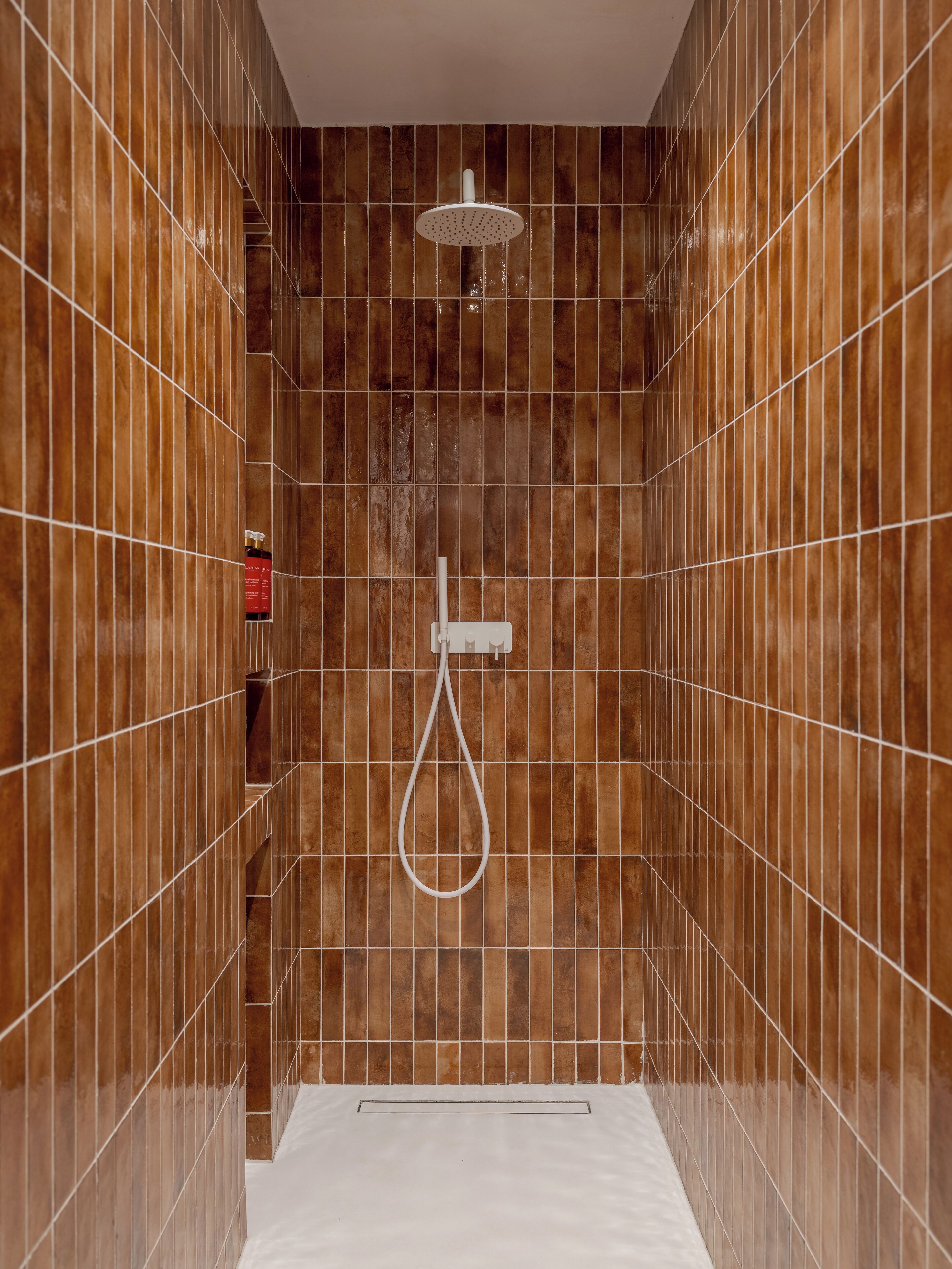 Una ducha moderna con cabezal de ducha de mano y panel de control en la pared.