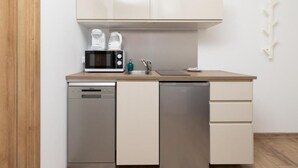 A compact kitchen with a dishwasher, a microwave, and a sink. - TOTU Home Gdańsk Marina Studio Old Town (Gdansk)