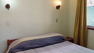 Un dormitorio con cama, dos lámparas de pared, una ventana con cortinas e iluminación en el techo.