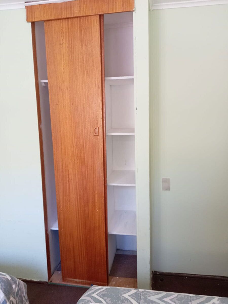 Une pièce avec une armoire en bois, une porte blanche et un sol carrelé.
