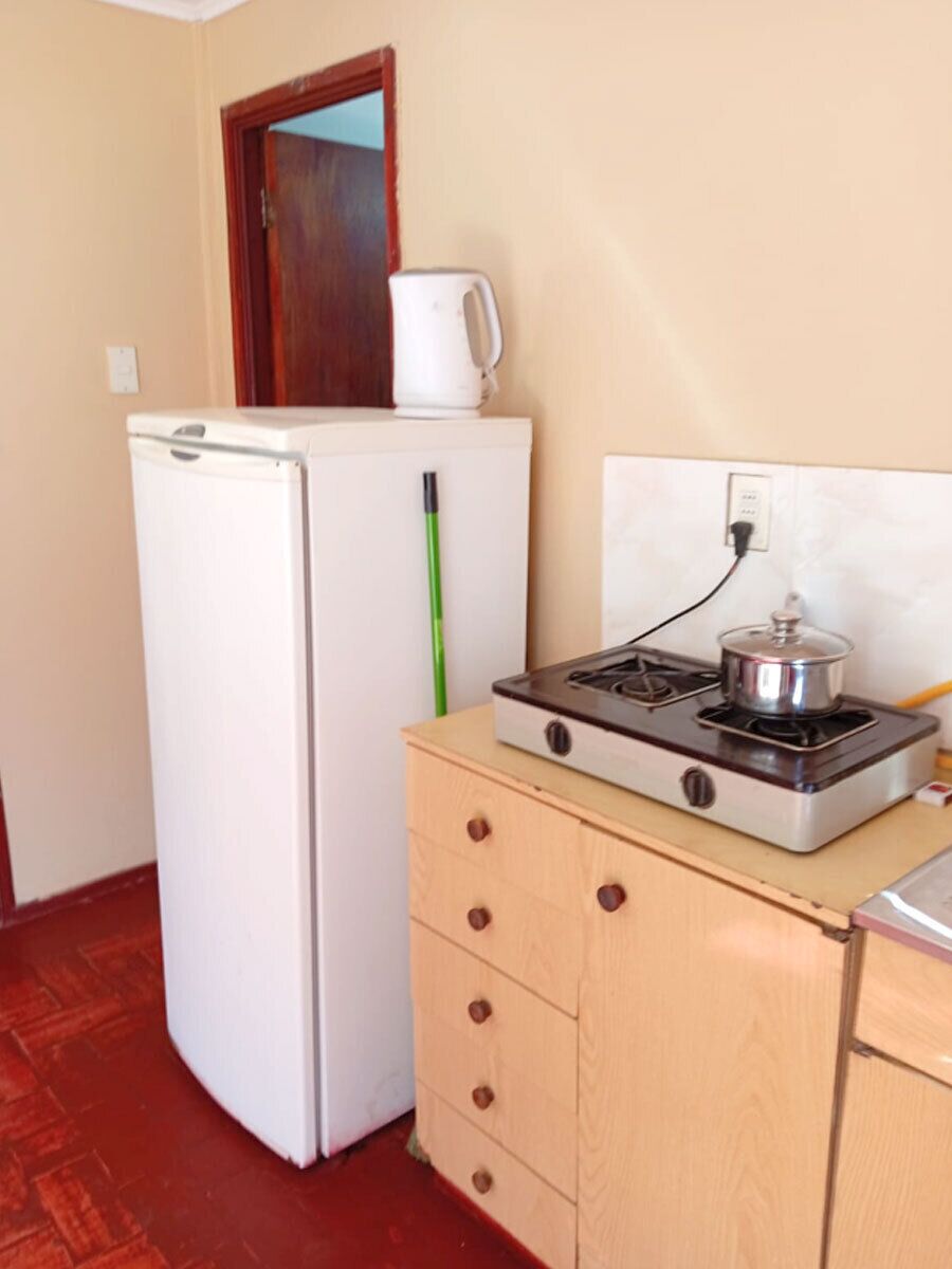 Una cucina compatta con frigorifero, fornello e pensile in legno.