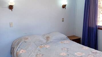A bedroom with a bed, two wall-mounted lamps, a window with curtains, and a ceiling fan.