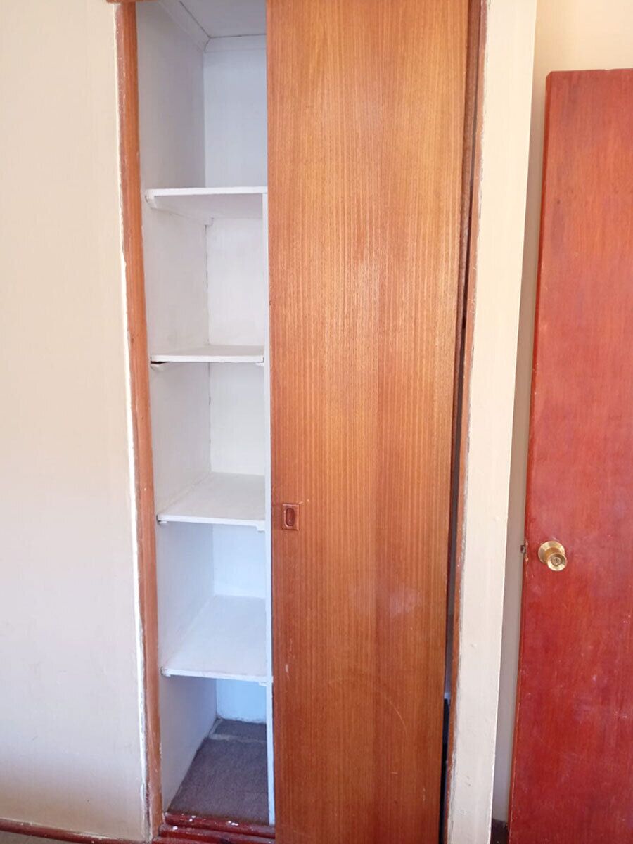 A wooden door with a white shelf unit inside.