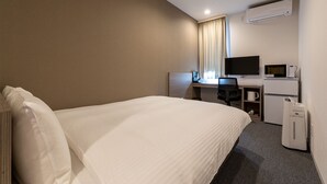 Quarto de hotel com cama, escrivaninha com computador, televisão e micro-ondas.