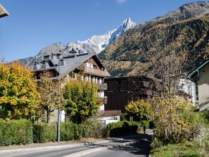 A mountain town with traditional wooden buildings, a clear road, and a prominent mountain in the background.