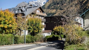 A mountain town with traditional wooden buildings, a clear road, and a prominent mountain in the background. - 3P Apartment Chamonix, Close to Slopes, Pets Allowed, Parking, WiFi (Chamonix-Mont-Blanc)