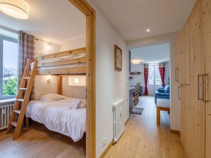 Una habitación con literas, suelo de madera, un radiador, un escritorio y vistas al exterior.