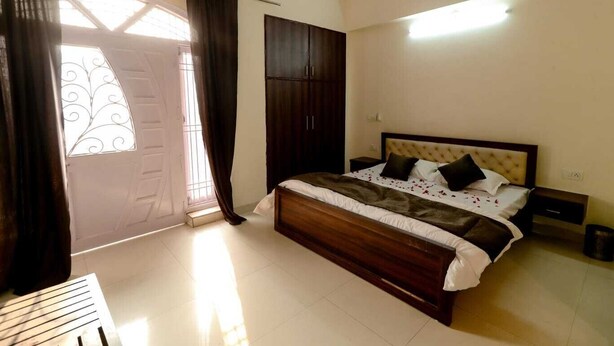 Une chambre à coucher avec un grand lit, une armoire, une table de chevet et une fenêtre avec des rideaux.