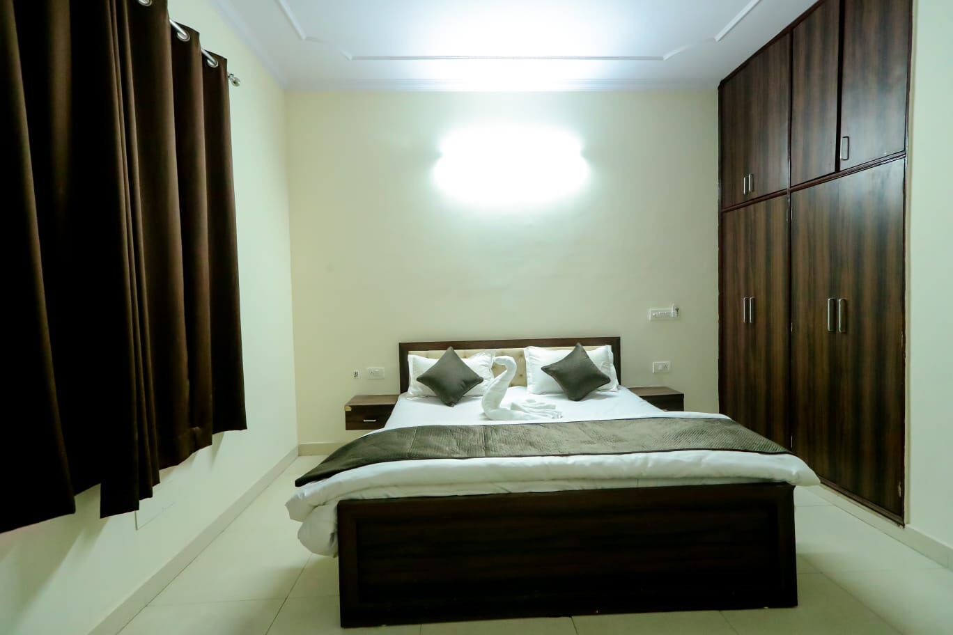 Un dormitorio con cama, cortinas, armario y mesita de noche.