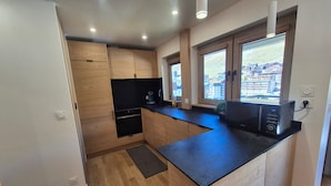 Una cucina moderna con mobili in legno, un piano di lavoro nero e un forno a microonde integrato.