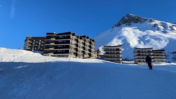 Una montagna innevata con moderni edifici a più piani sullo sfondo.