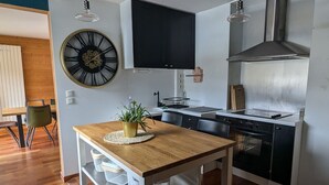 Una cocina moderna con una mesa de madera, un reloj grande y una estufa empotrada.