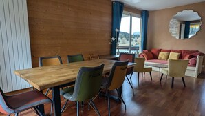Un área de comedor con una mesa y sillas de madera, un sofá y un espejo grande.