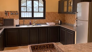 Una cocina con armarios oscuros, un ventanal grande y una bandeja decorativa sobre la encimera.