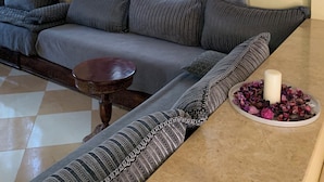 Una sala de estar con un sofá, una mesa redonda de madera y un plato decorativo con flores.