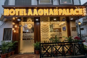 Entrada de un hotel con un cartel que dice 'Hotel Aagman Palace' y un letrero de bienvenida.
