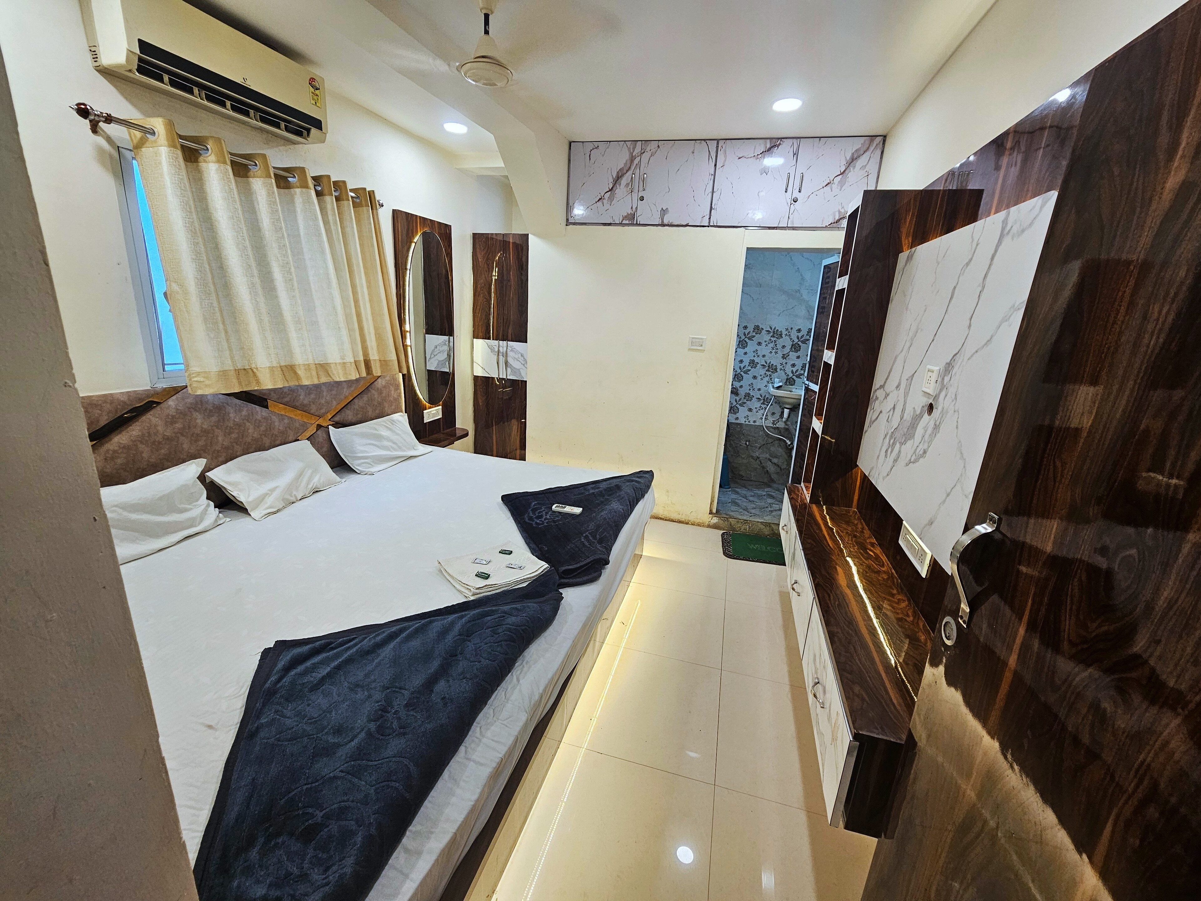 A hotel room with a bed, a vanity with a mirror, a sink, and a shower area.