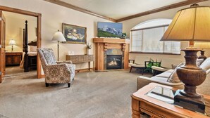 A cozy living room with a patterned armchair, a fireplace, a television, and a lamp. - 2BR, 2BA villa with full kitchen, pool, hot tub, and valley views. 2057-2 (Midway)