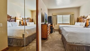 Quarto de hotel com duas camas, uma cômoda, uma escrivaninha e uma televisão.