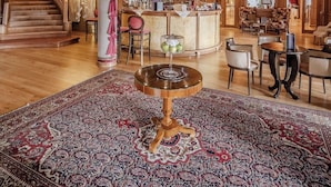 A grand lobby with a staircase, a bar area, and a round table with a glass centerpiece. - HOTIDAY Room Collection - Campiglio Pradalago (Pinzolo)