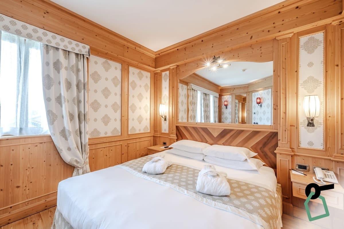 Une pièce aux murs lambrés, avec un lit, un miroir et un téléphone.