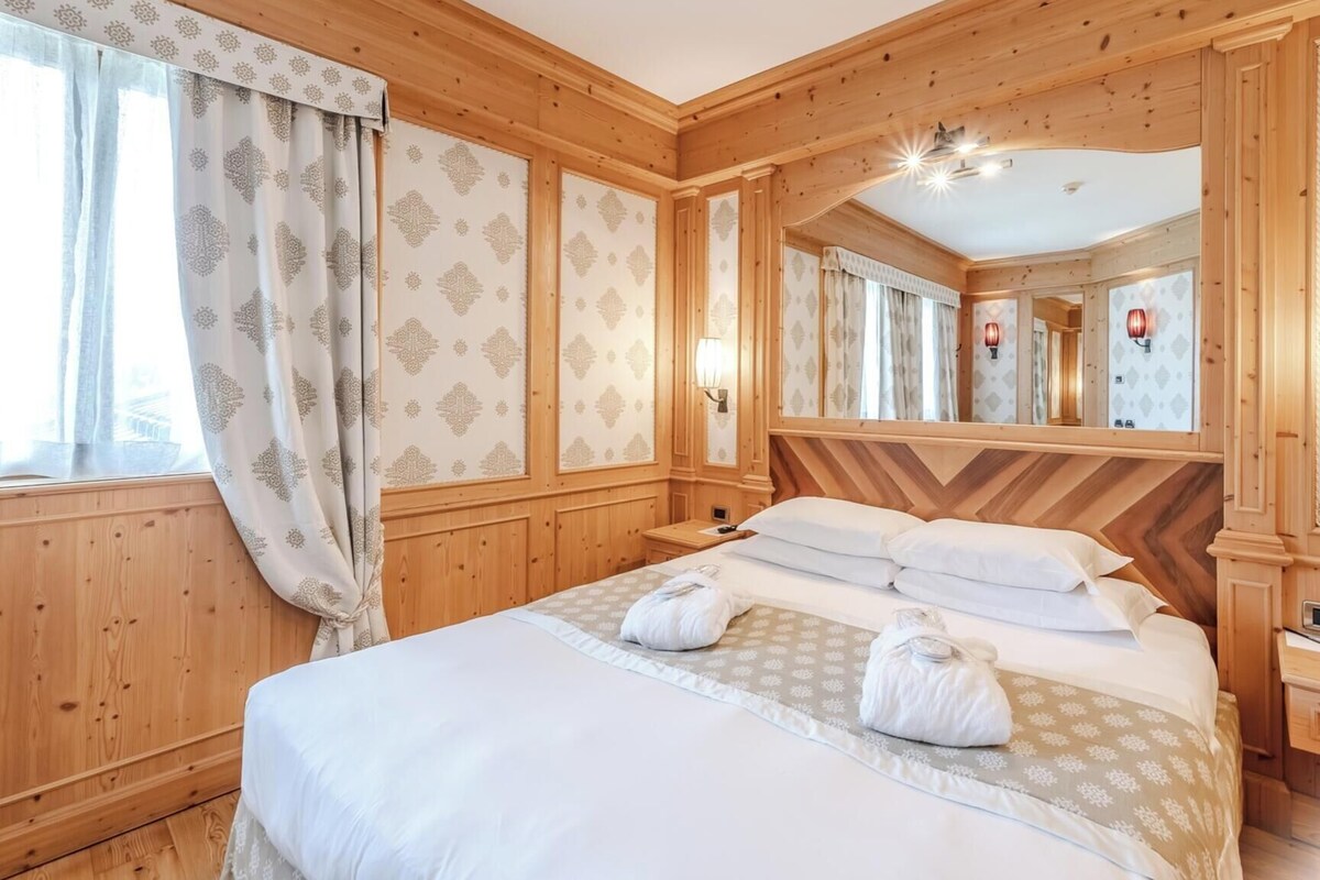 Een kamer met houten lambrisering, een bed, een spiegel en een telefoon.