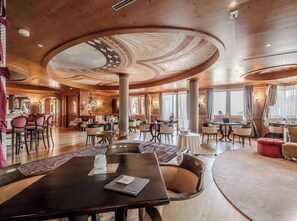 Een ruime hotellobby met een hoge plafond, verschillende zithoeken en grote ramen.