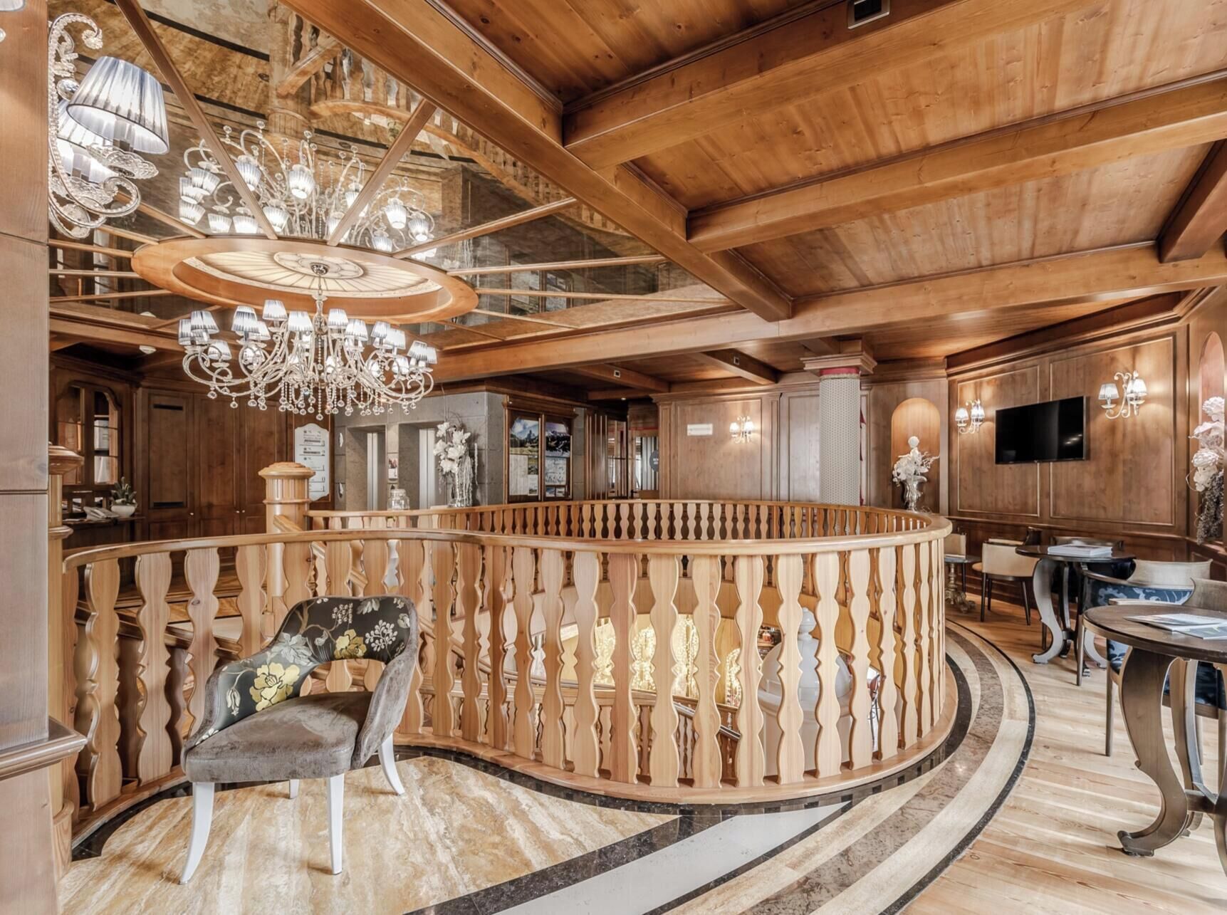 Um interior imponente com escada de madeira, um candelabro e um corrimão redondo de madeira.