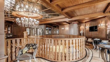 Um interior imponente com escada de madeira, um candelabro e um corrimão redondo de madeira.