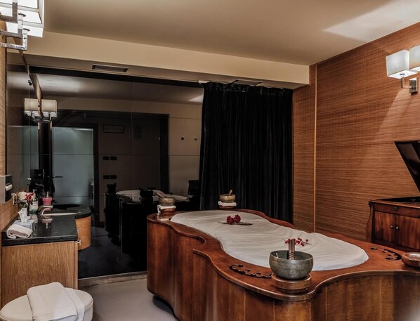 A modern bathroom with a wooden vanity, a large mirror, and a massage table with a stone basin. - HOTIDAY Room Collection - Campiglio Pradalago (Pinzolo)