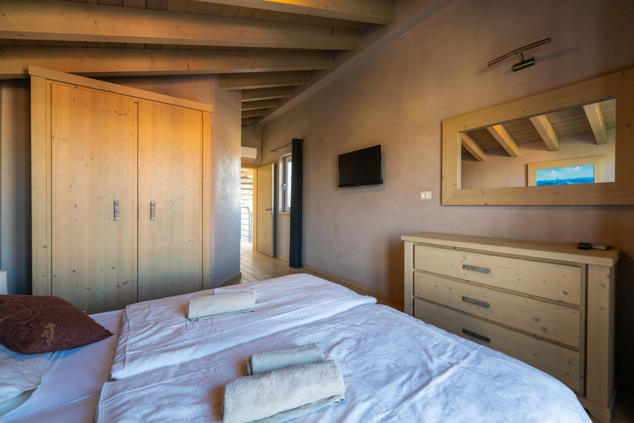 A bedroom with two beds, wooden wardrobe, and a dresser.