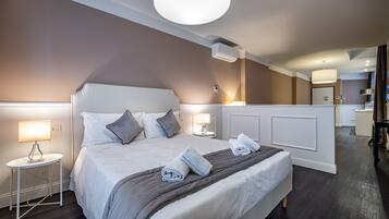 Een moderne hotelkamer met een groot bed, bedlampen, een ronde plafondlamp en een zichtbare badkamer op de achtergrond.
