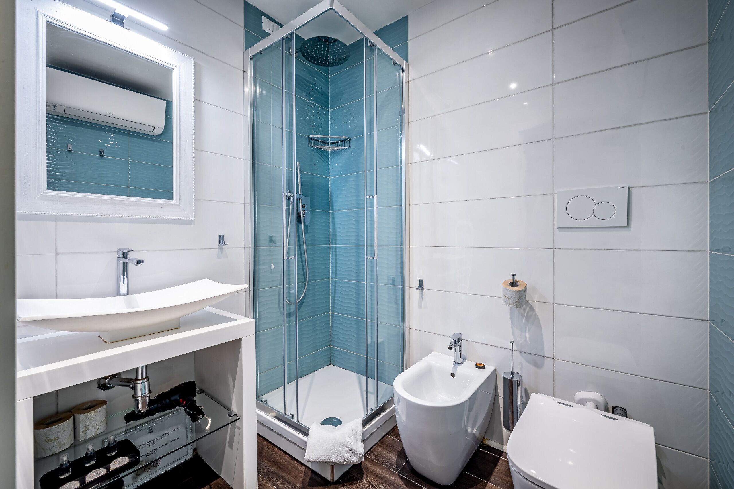 Un baño moderno con ducha envuelta en vidrio, lavamanos blanco y bidé.